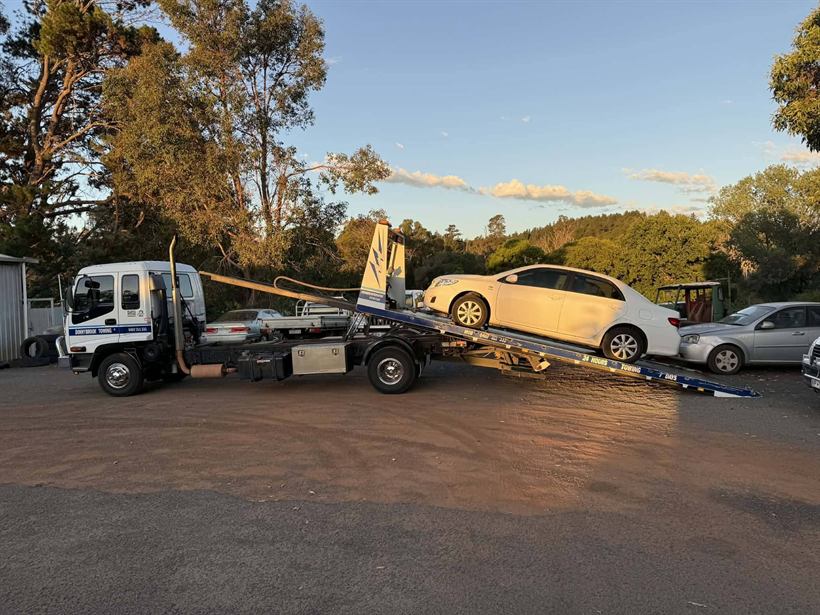 Tilt tray loading a sedan in golden hour light
