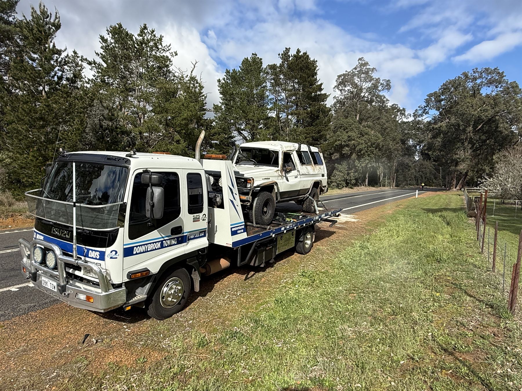 Donnybrook Towing tilt tray carrying a rolled LandCruiser Troopy on a country road